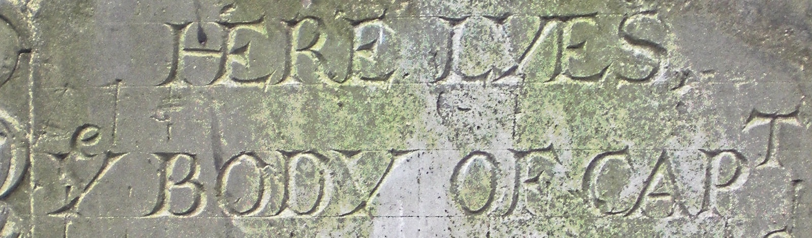 Carved gravestone lettering HERE LYES ye BODY OF CAPT with a small e above the Y
