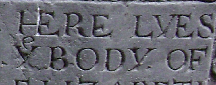 Carved gravestone lettering HERE LYES ye BODY OF, small e above the Y