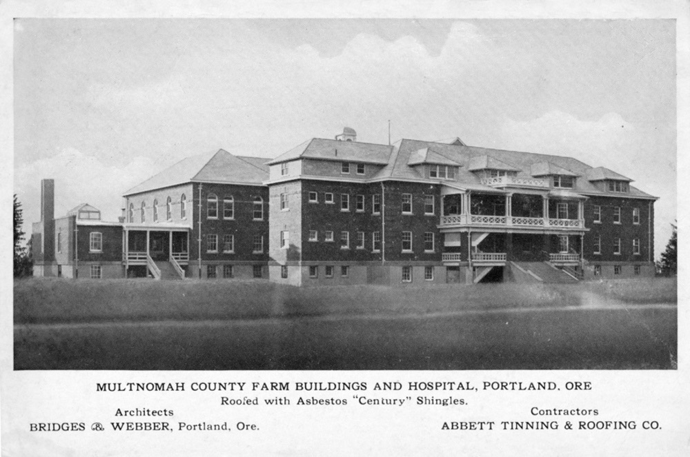 Postcard view of a large brick building with porches and dormers set in a grassy field, labeled Multnomah County Farm Buildings and Hospital