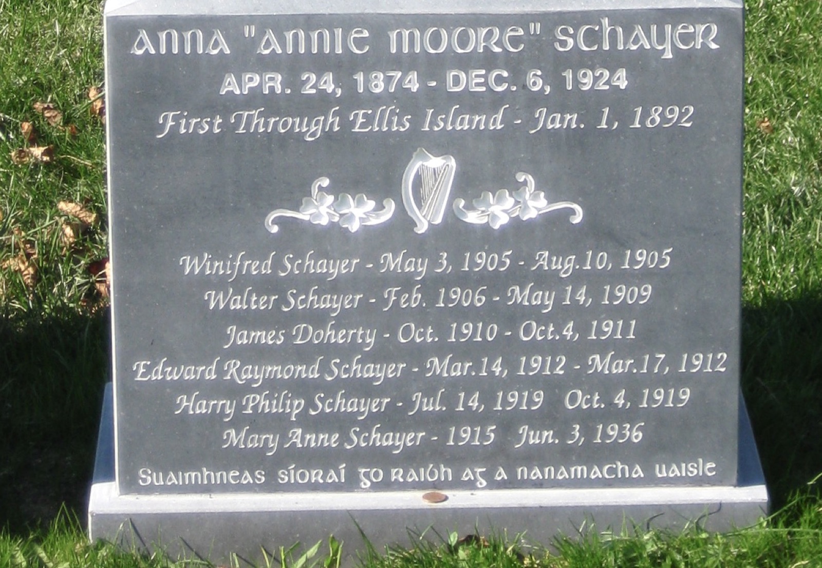 Base of a stone Celtic cross: Anna Annie Moore Schayer, Apr. 24, 1874 to Dec. 6, 1924, First Through Ellis Island, Jan. 1, 1892, followed by six names with dates.